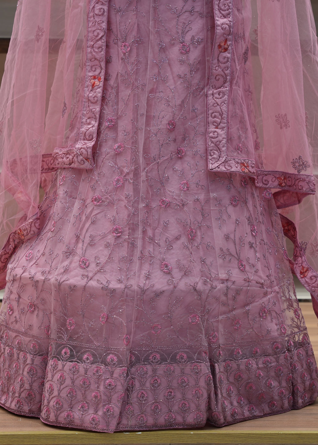 Pink embroidered traditional outfit with a sheer pink dupatta on a wooden surface.