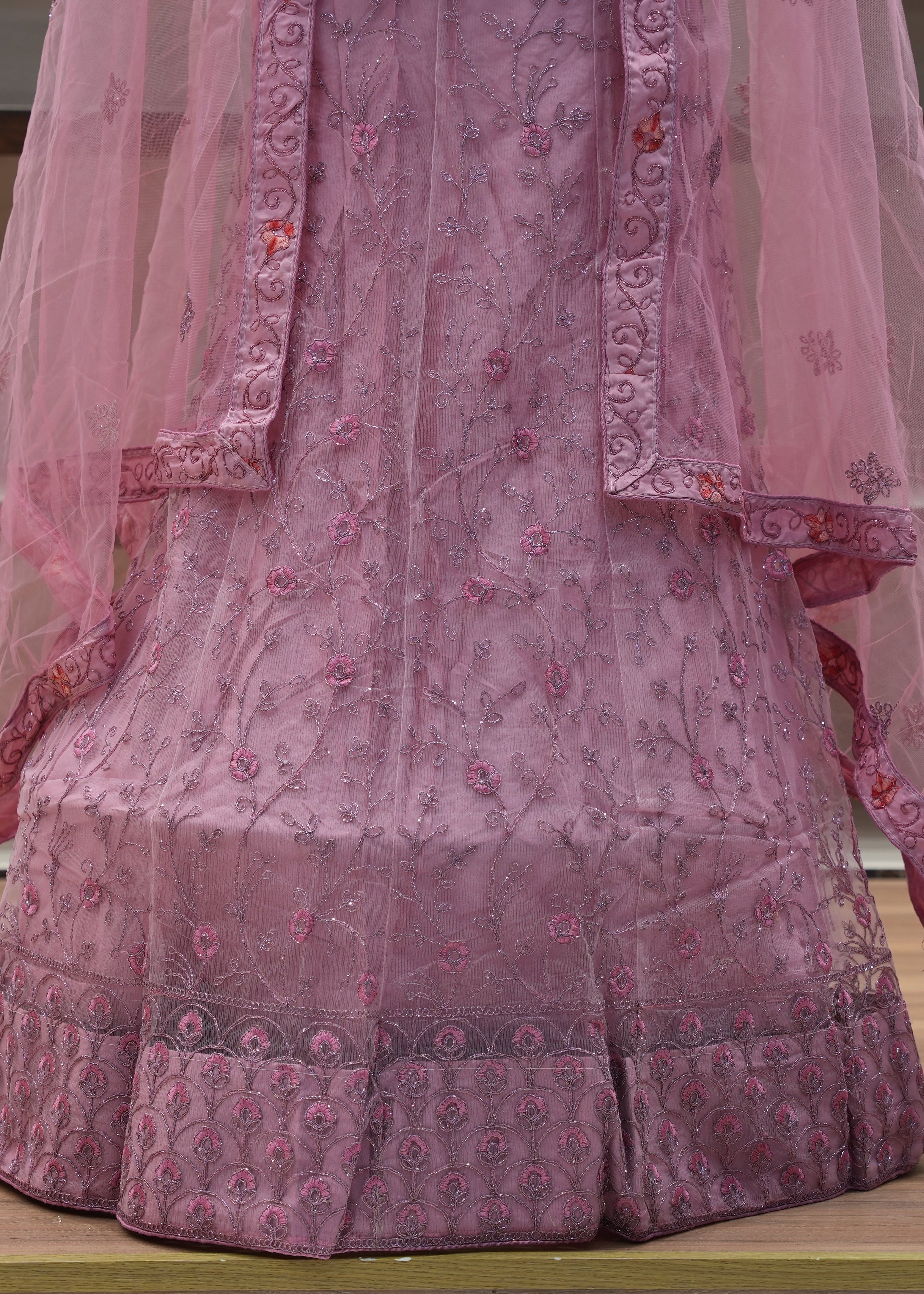 Pink embroidered traditional outfit with a sheer pink dupatta on a wooden surface.