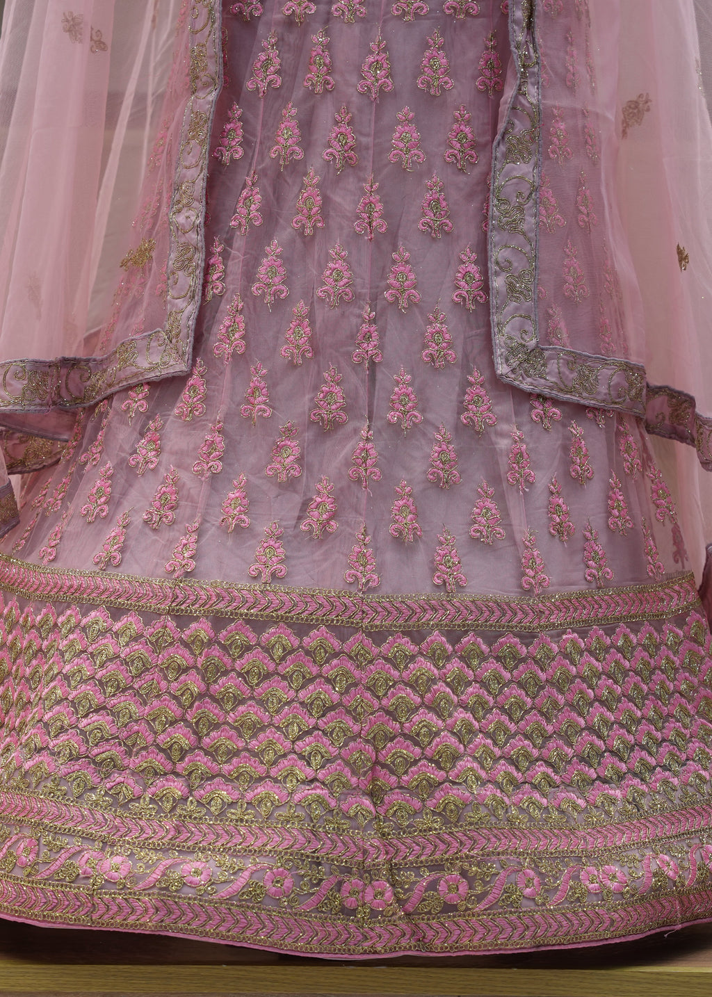 Pink embroidered traditional outfit on a wooden surface