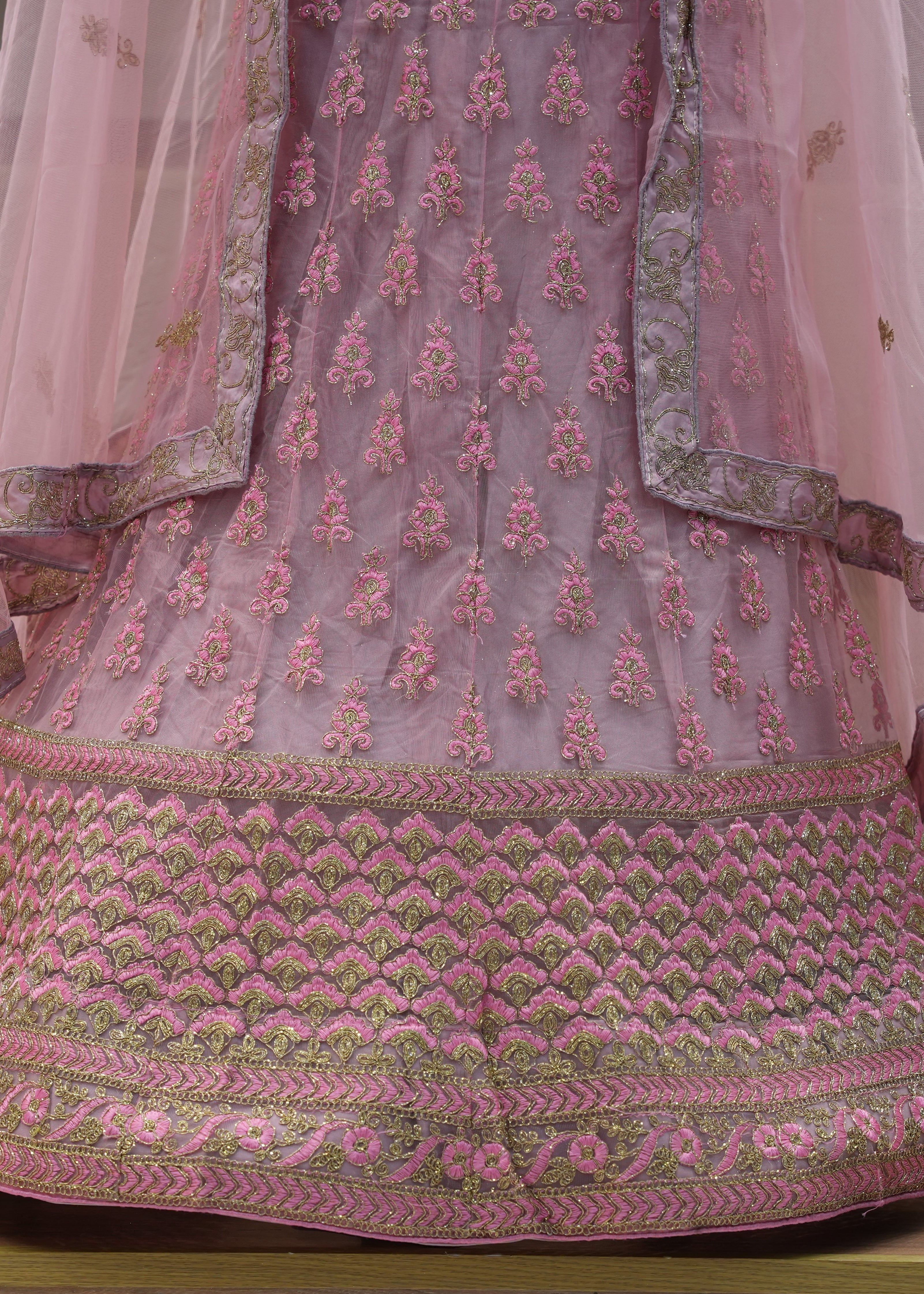 Pink embroidered traditional outfit on a wooden surface