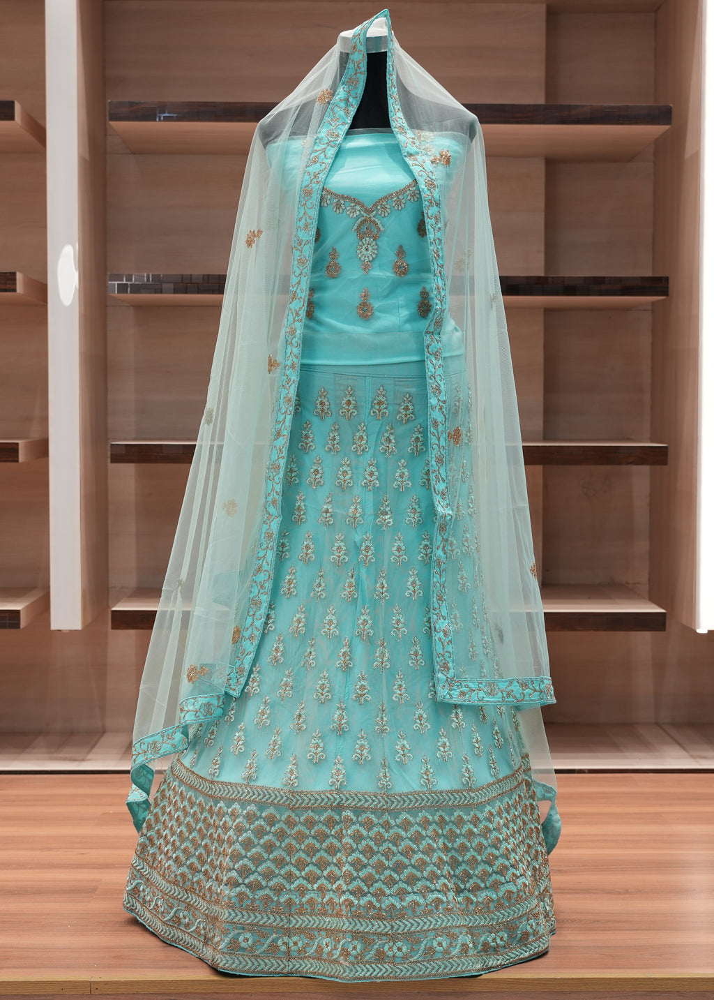 Turquoise embroidered traditional outfit with a dupatta on a wooden shelf background