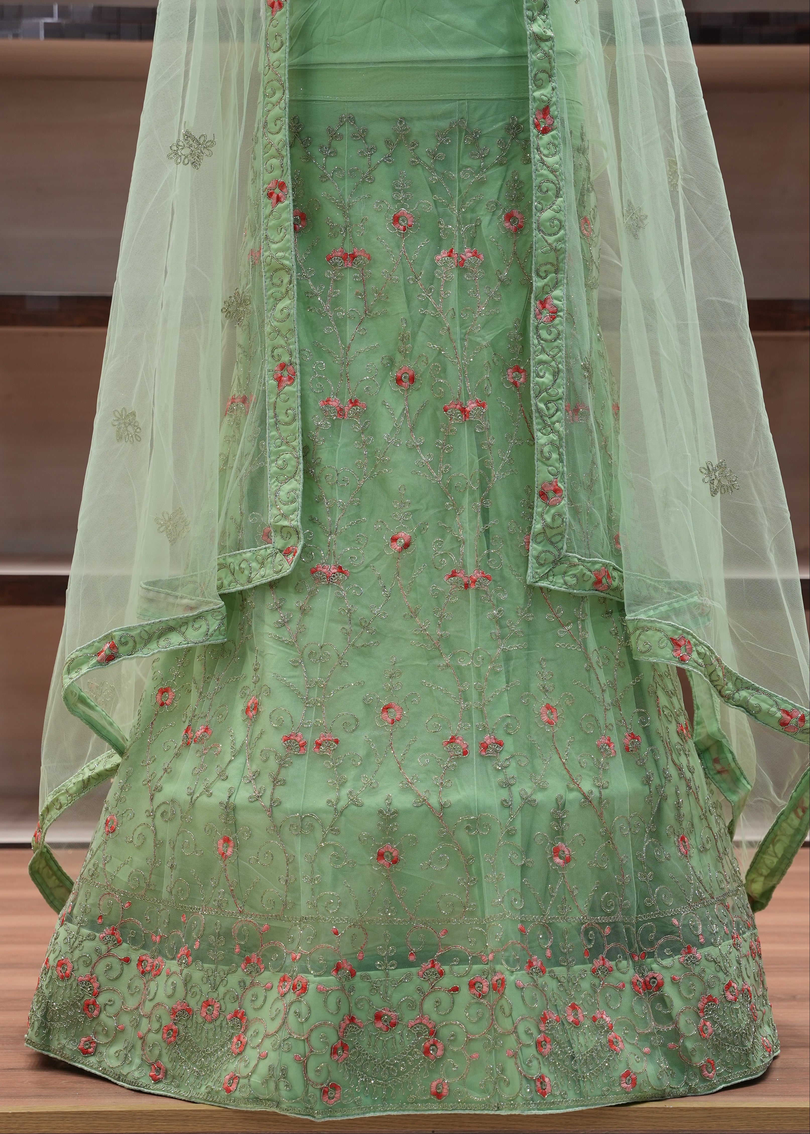 Green embroidered fabric with red patterns on a wooden surface