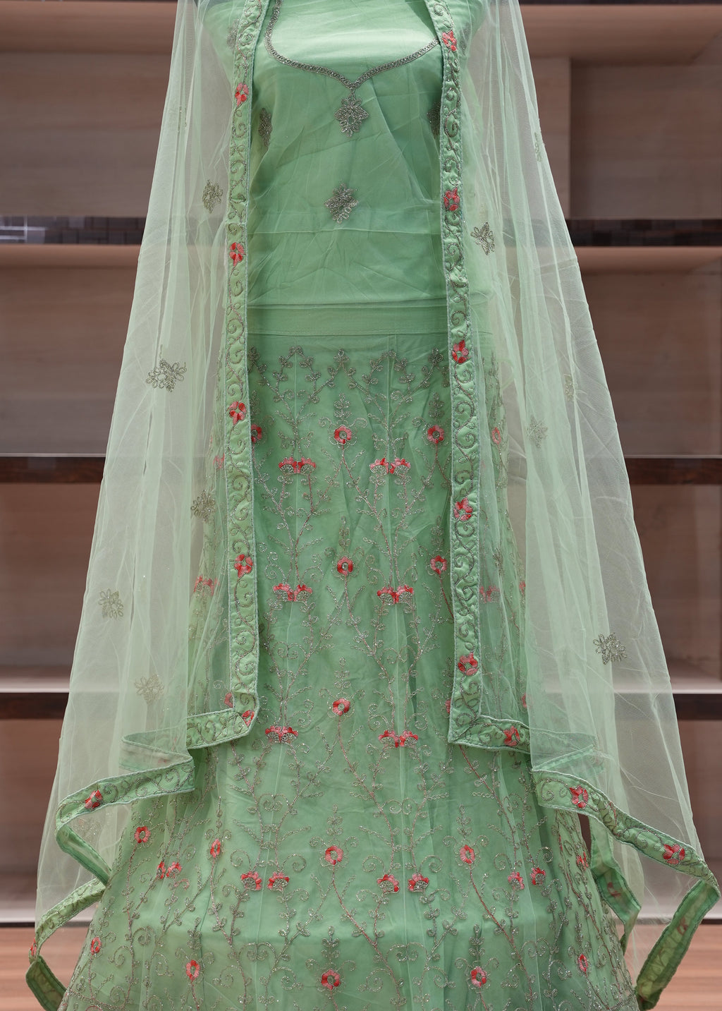 Green embroidered fabric on a wooden shelf