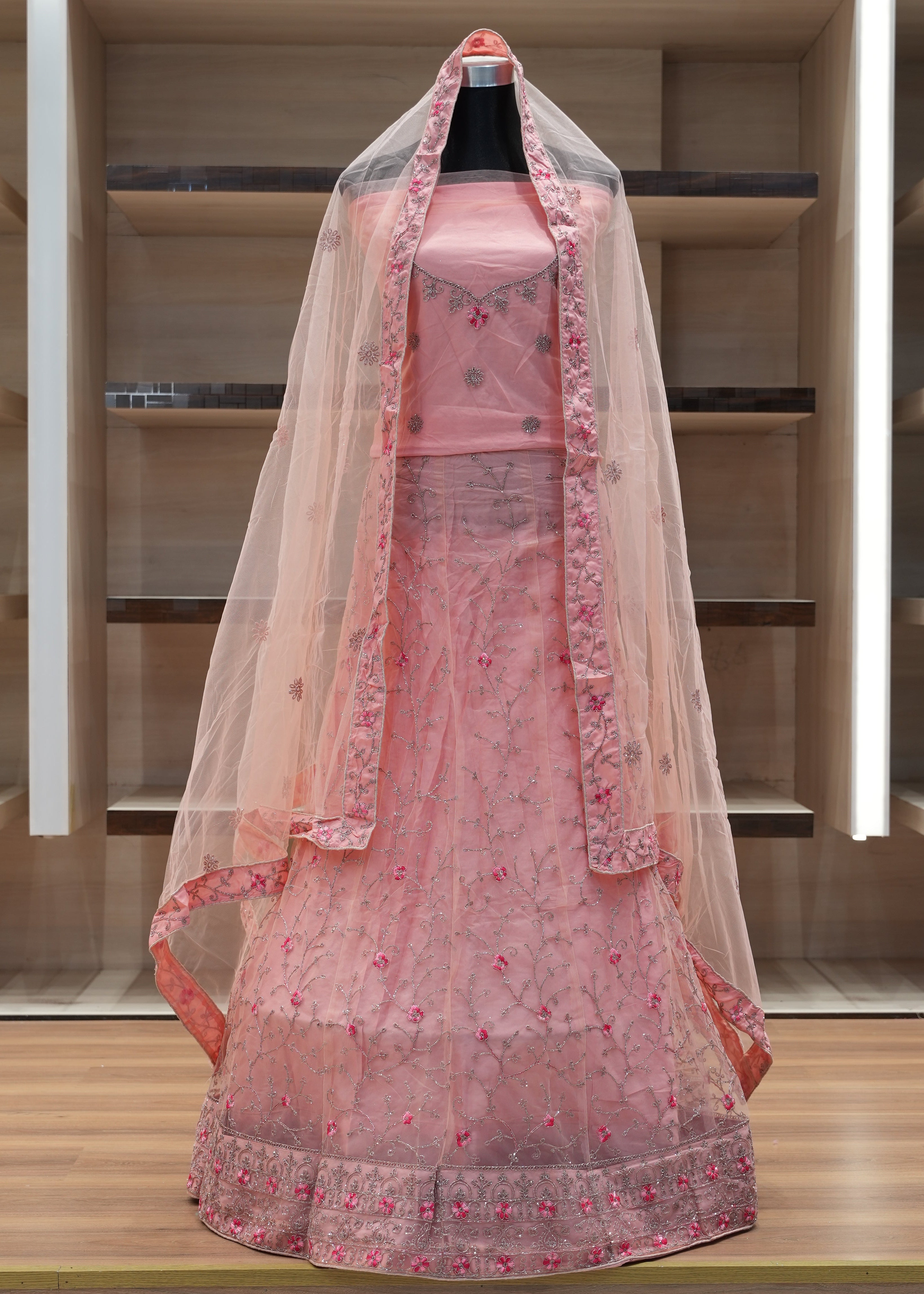 Pink floral dress in a clear plastic bag on a wooden shelf.