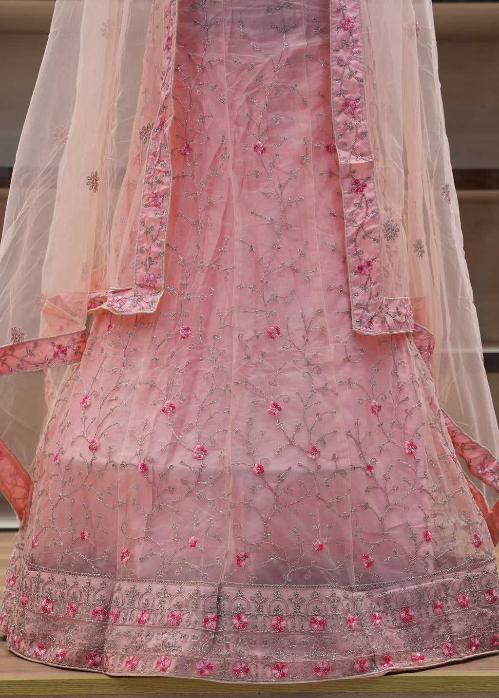Pink embroidered traditional outfit with a sheer dupatta on a chair.