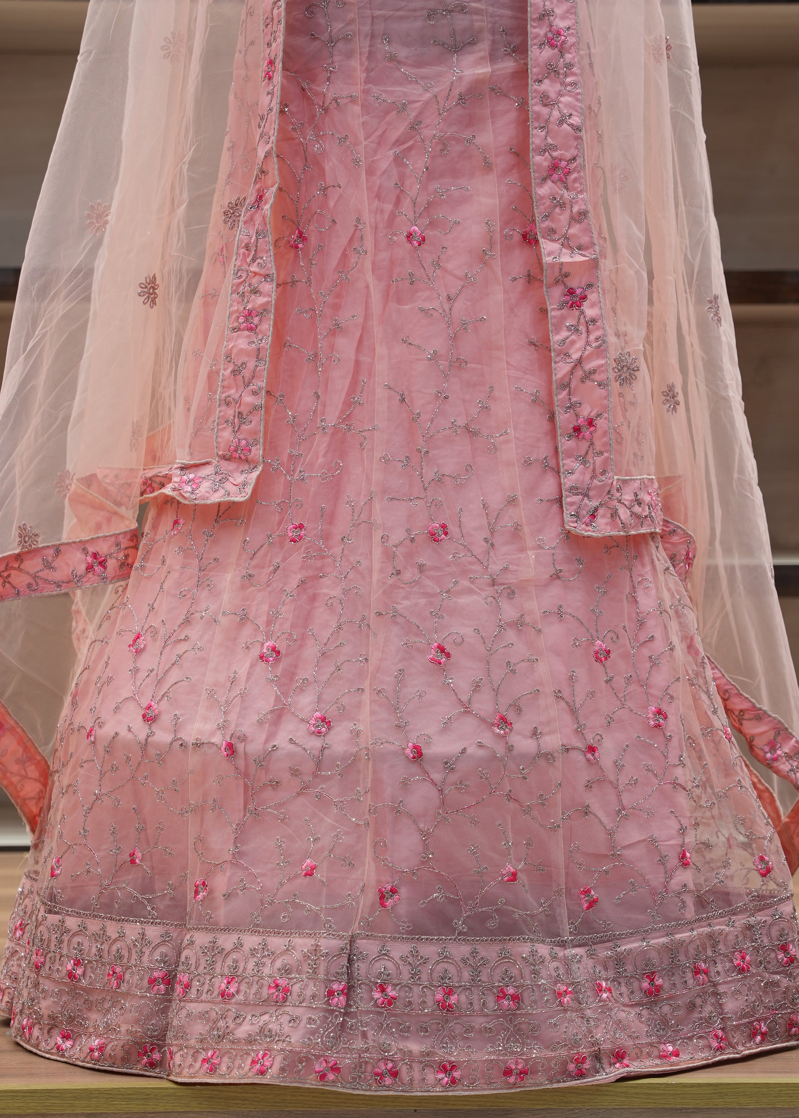 Pink embroidered traditional outfit with a sheer dupatta on a chair.