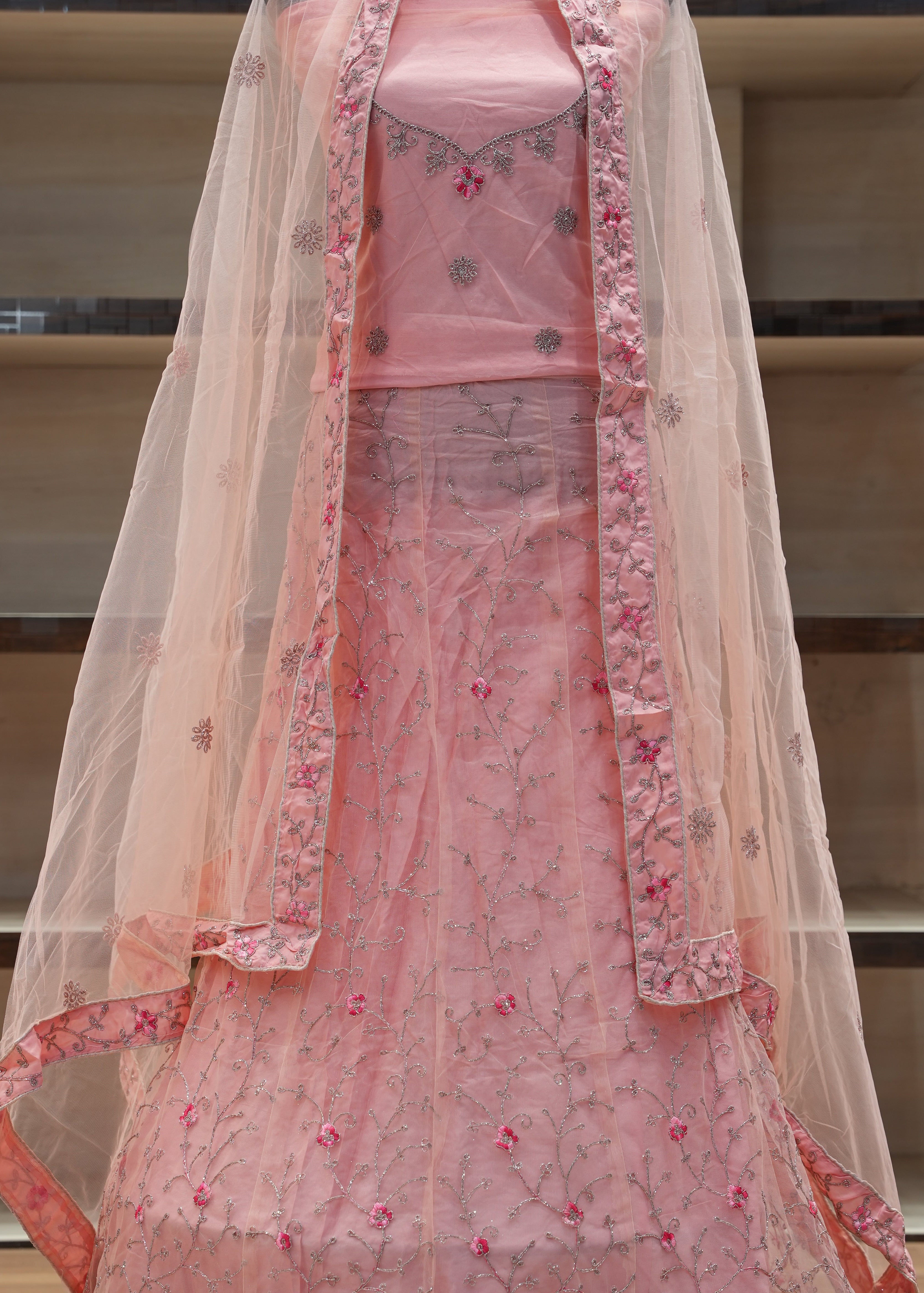 Pink embroidered bedspread with a net on a wooden bed frame.