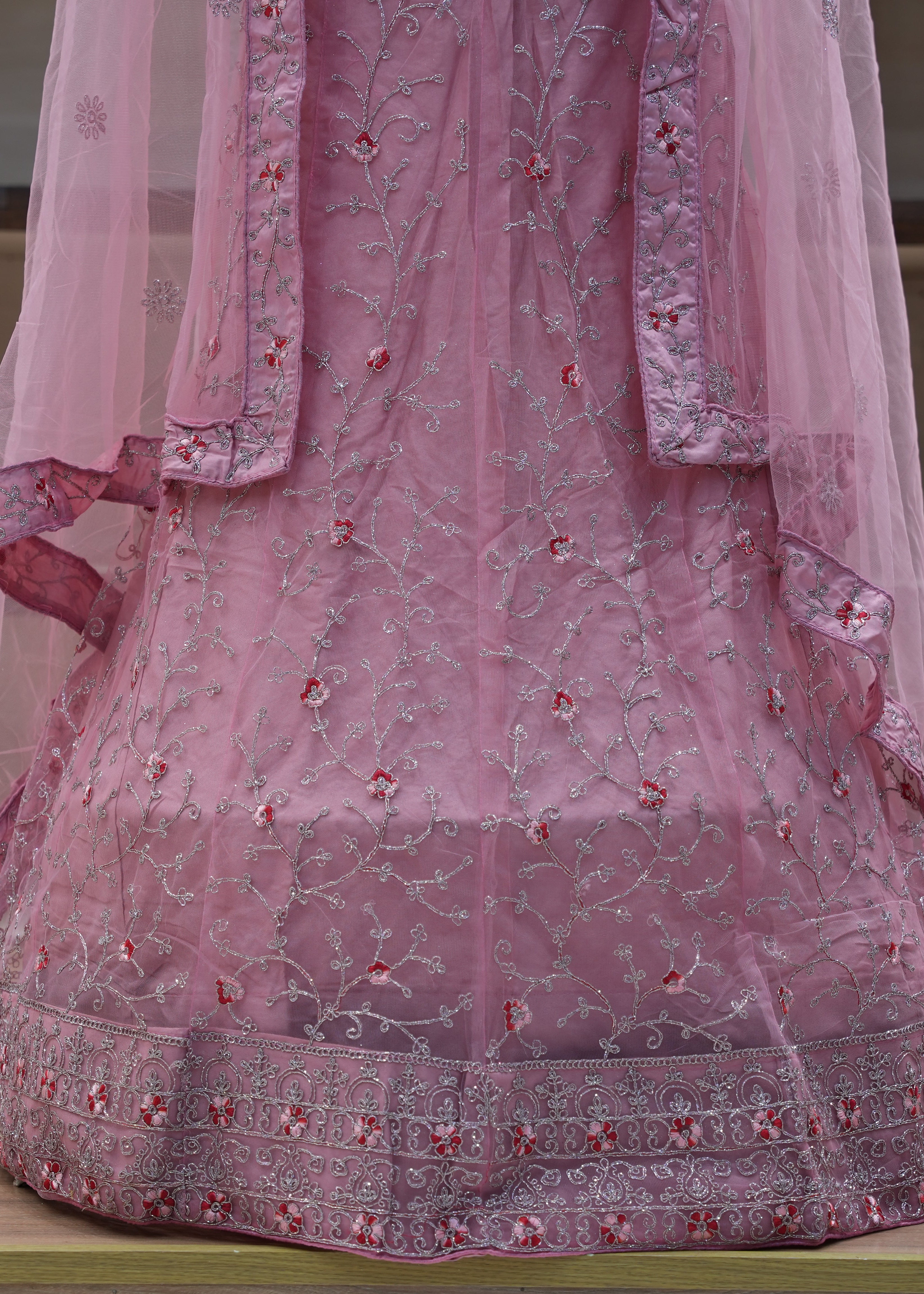 Pink embroidered traditional outfit on a wooden surface