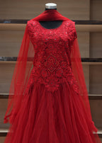 Red embroidered dress on a mannequin against a wooden shelf background