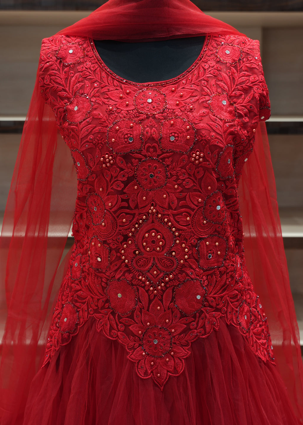 Red embroidered dress with a sheer overlay on a neutral background