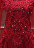 Close-up of a red embroidered fabric with intricate patterns and embellishments.