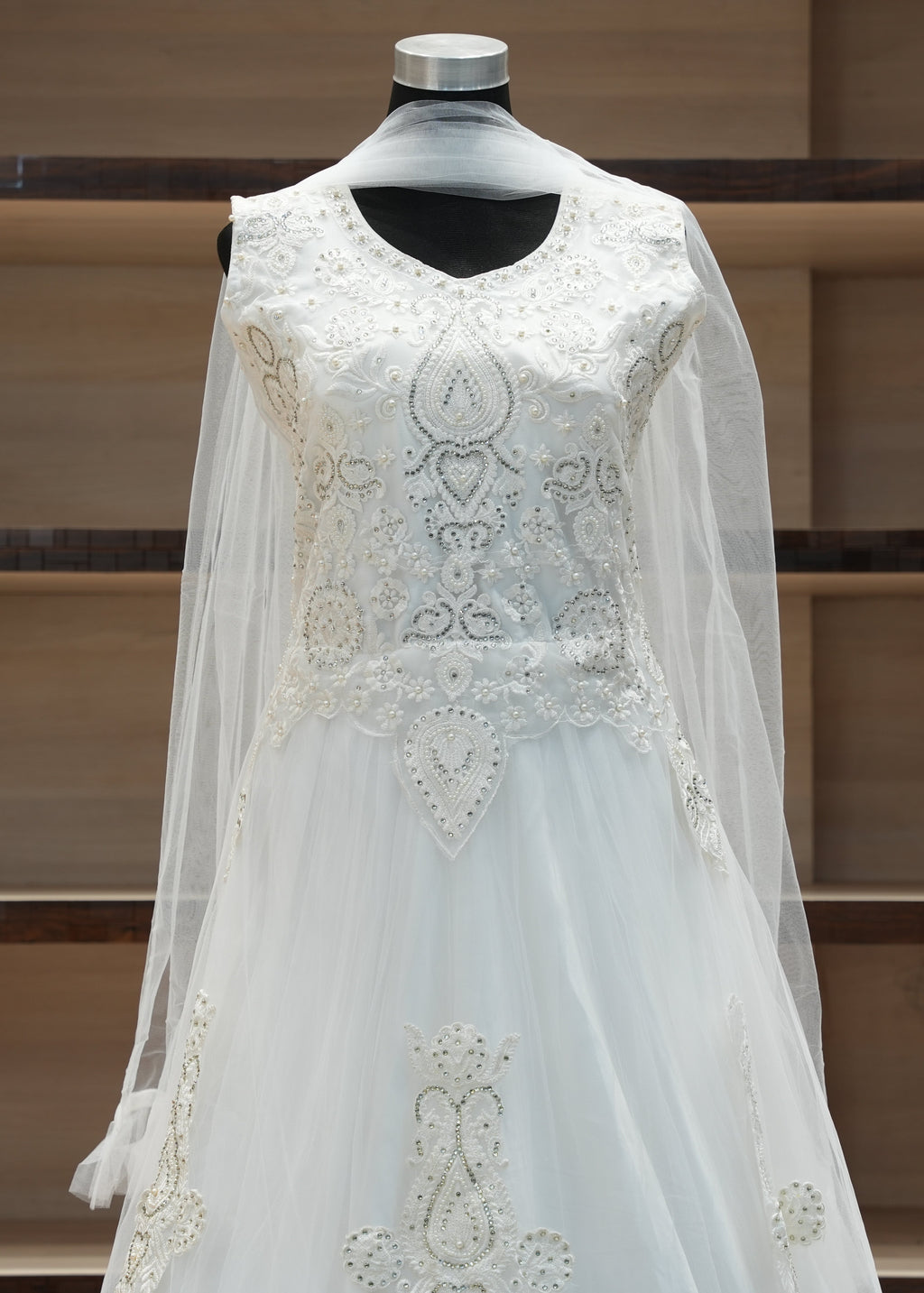 White embroidered dress on a mannequin against a wooden shelf background