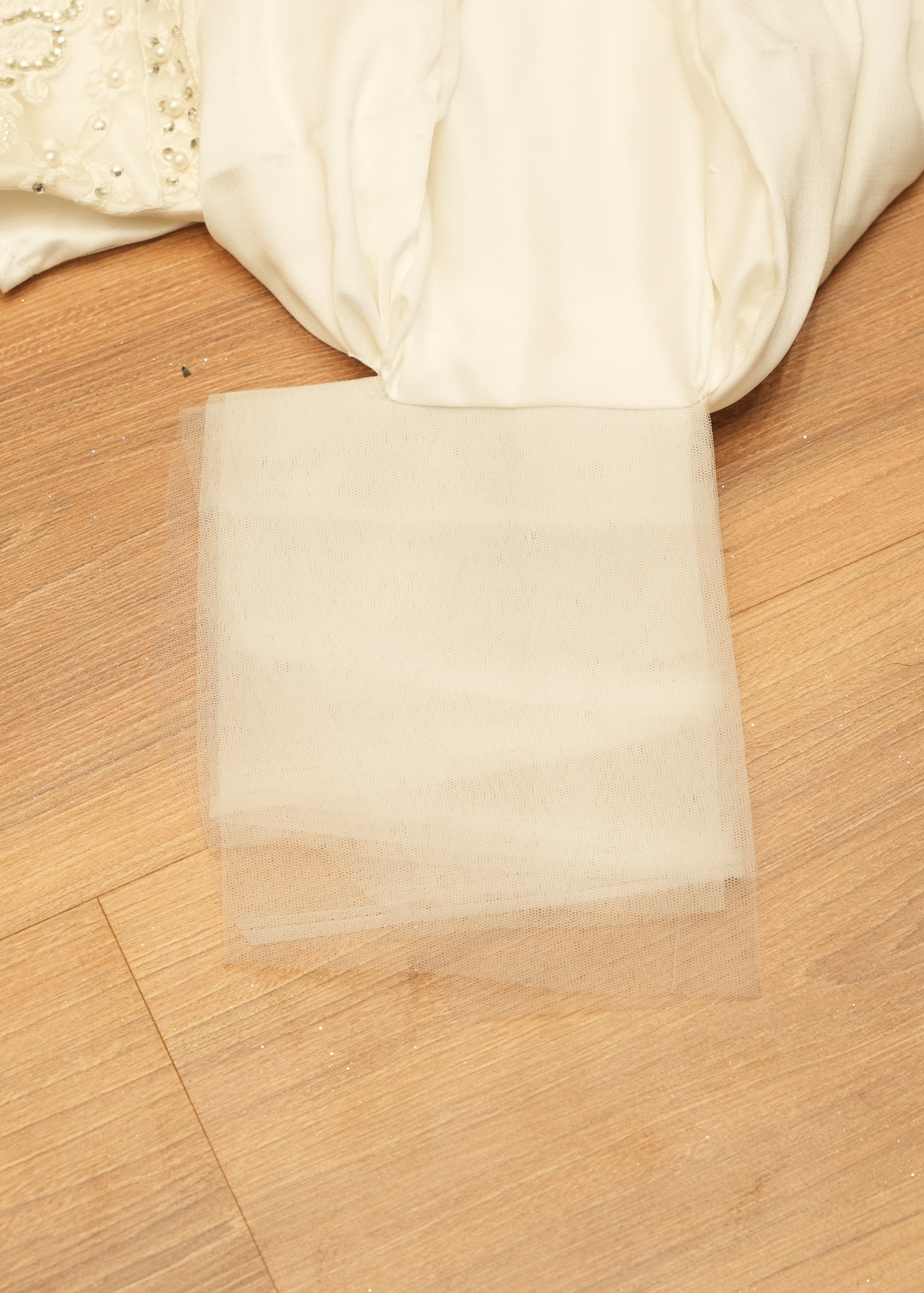 White fabric on a wooden surface with a clear square piece of paper.