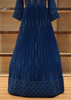 Blue pleated dress with gold detailing on a wooden surface