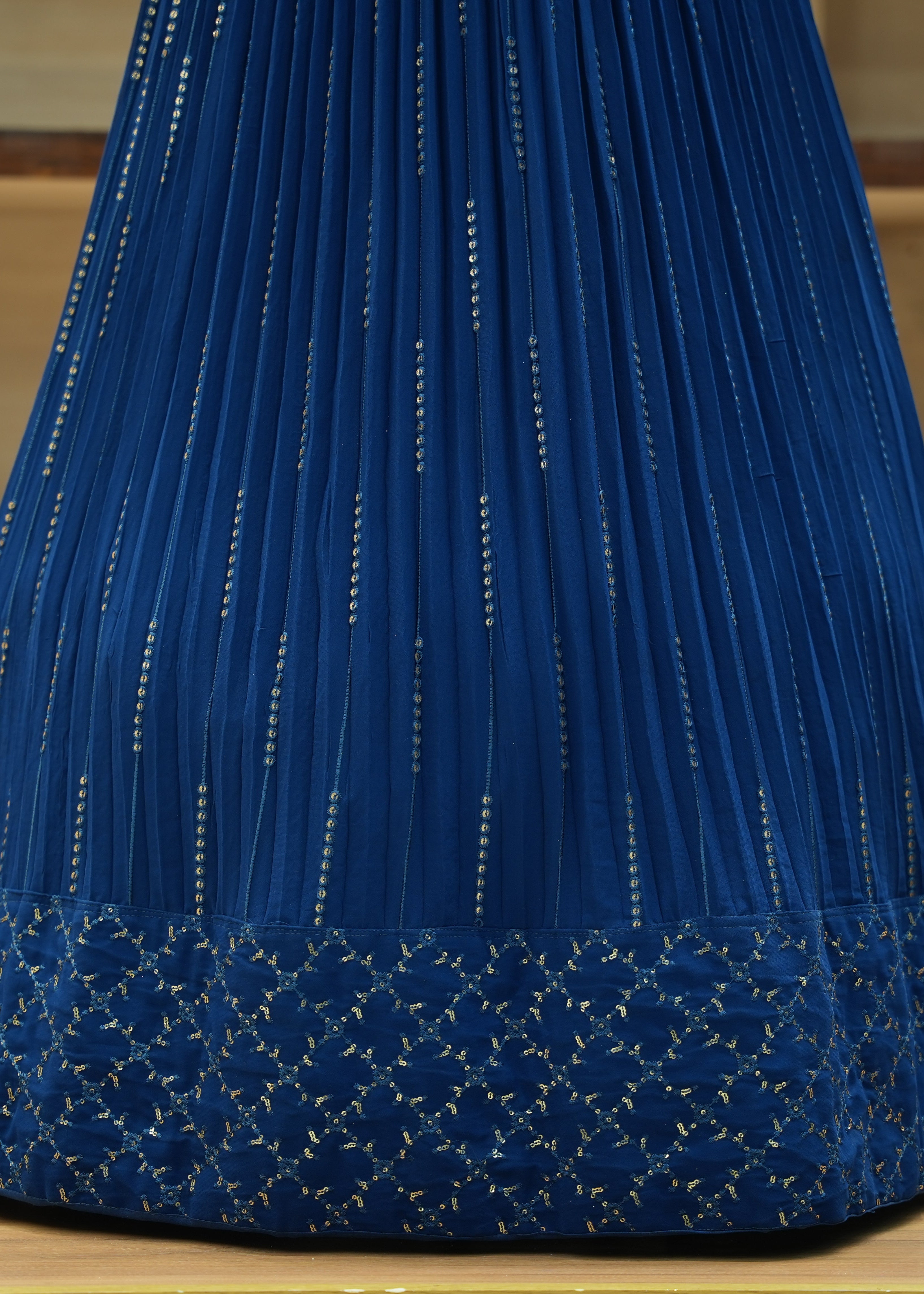 Blue pleated skirt with decorative patterns on a wooden surface
