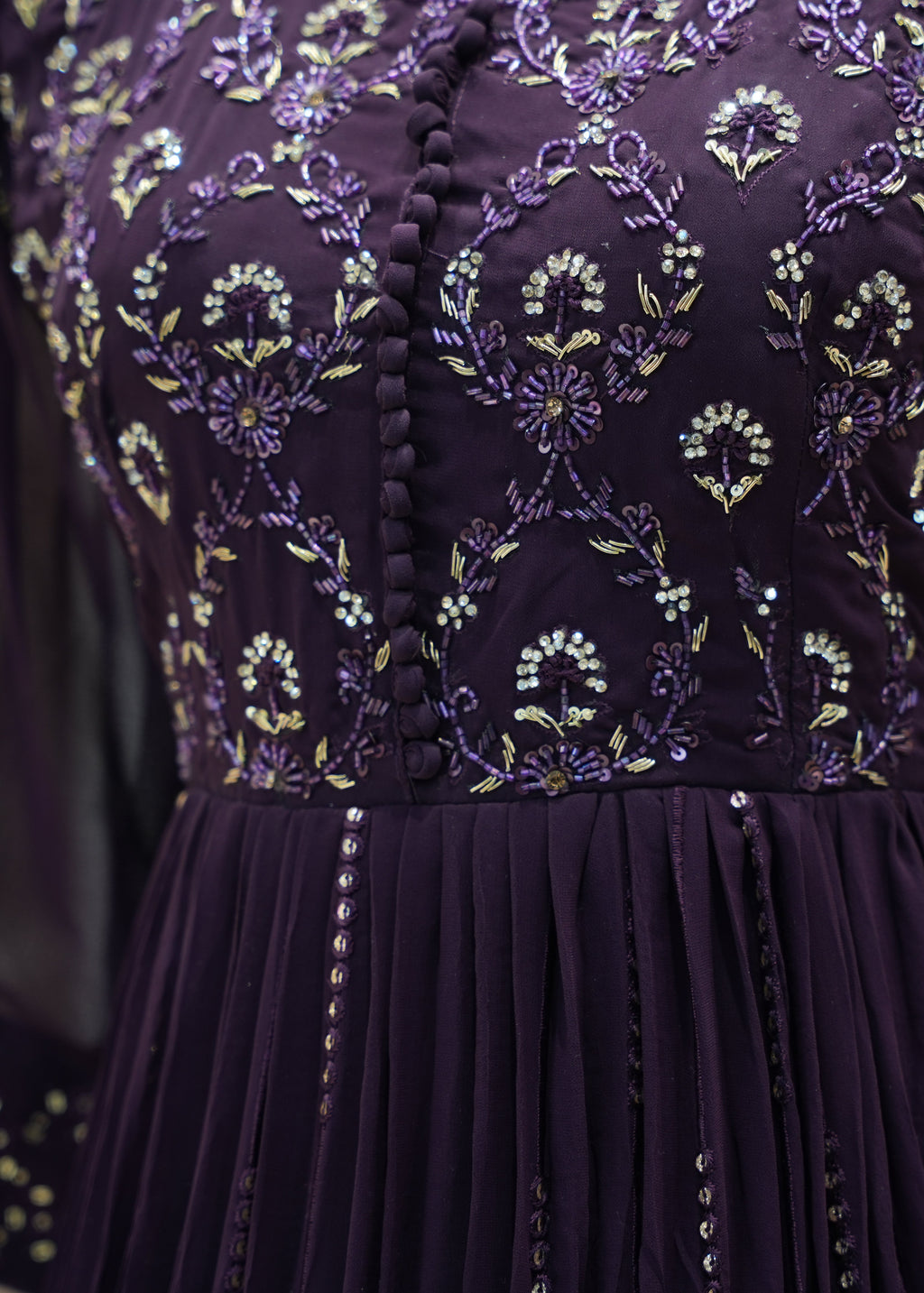 Close-up of a purple dress with intricate floral embroidery and sequin details.