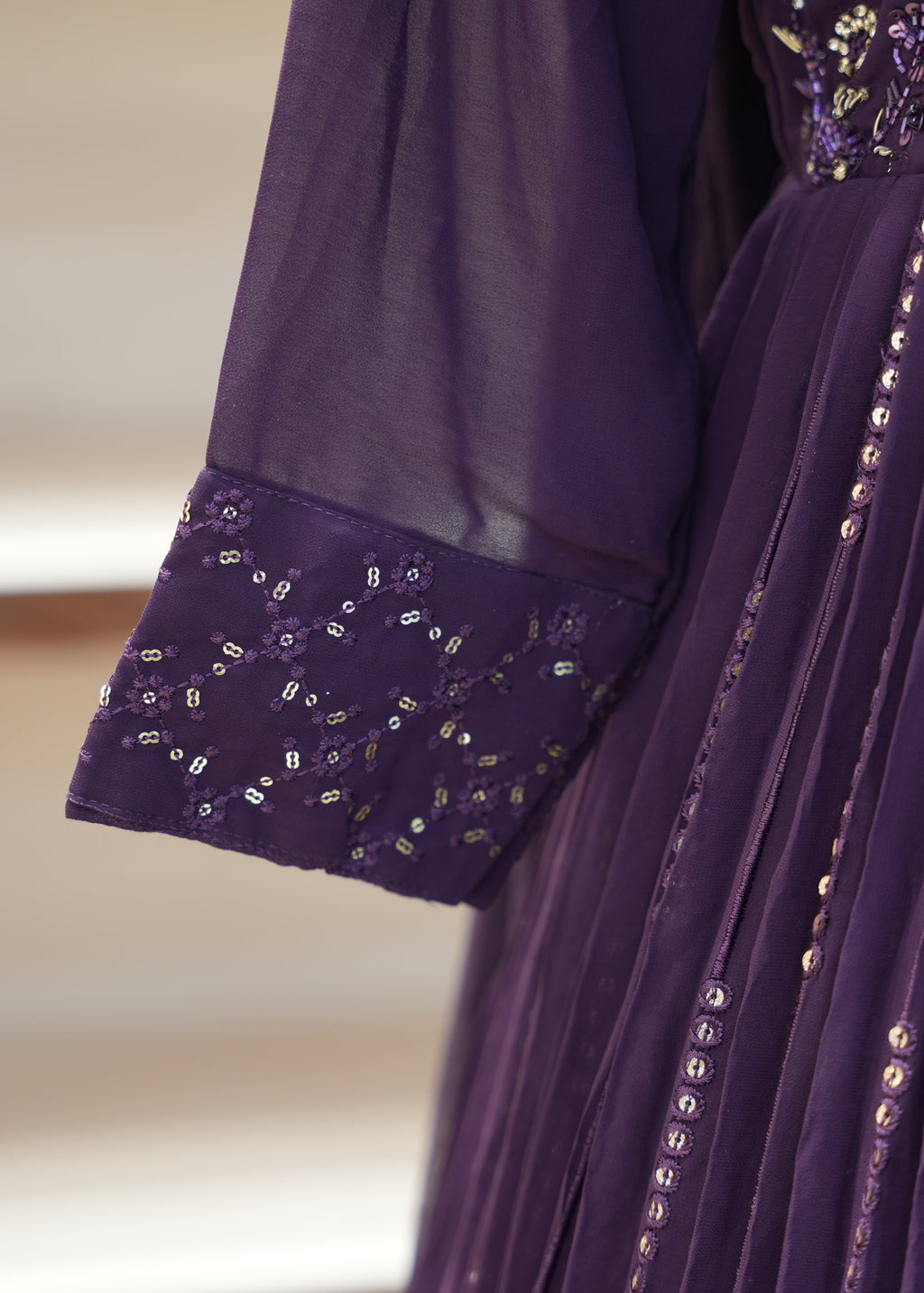 Close-up of a purple dress with floral embroidery and sequins on a blurred background