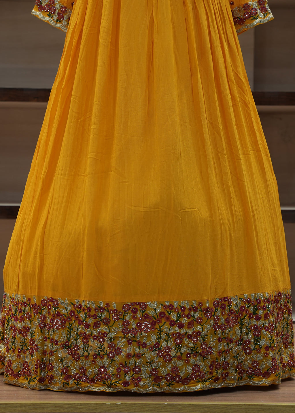 Yellow traditional outfit with floral patterns on a wooden floor