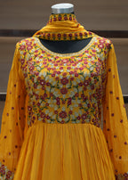 Yellow traditional outfit with floral patterns on a mannequin against a neutral background