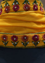 Yellow fabric with floral embroidery and beads on a dark background