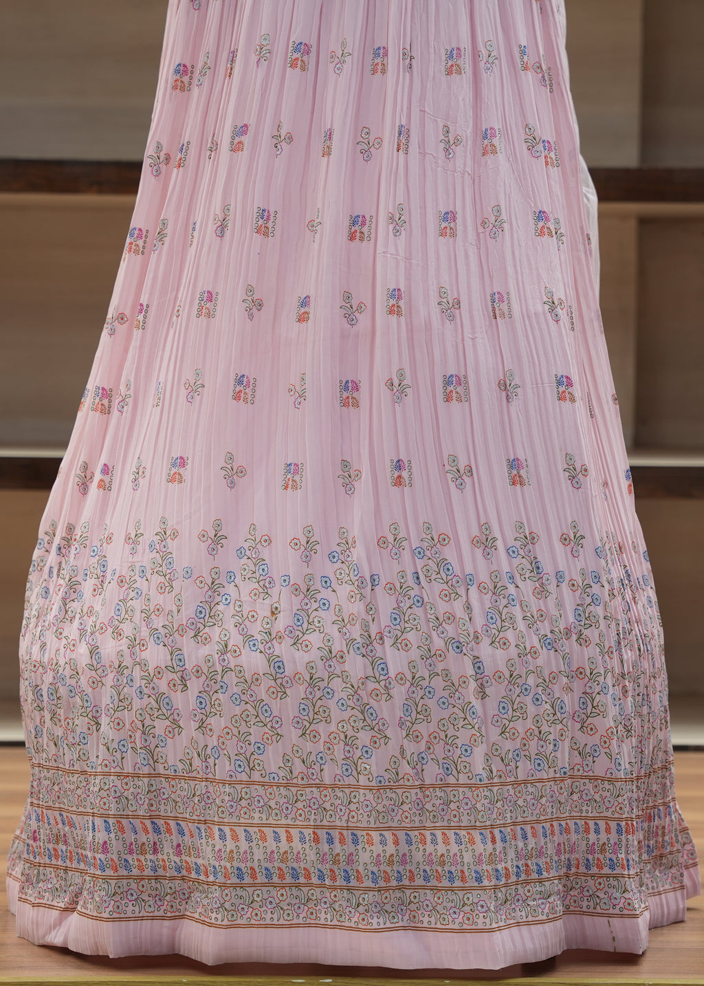 Pink embroidered traditional garment on a wooden surface