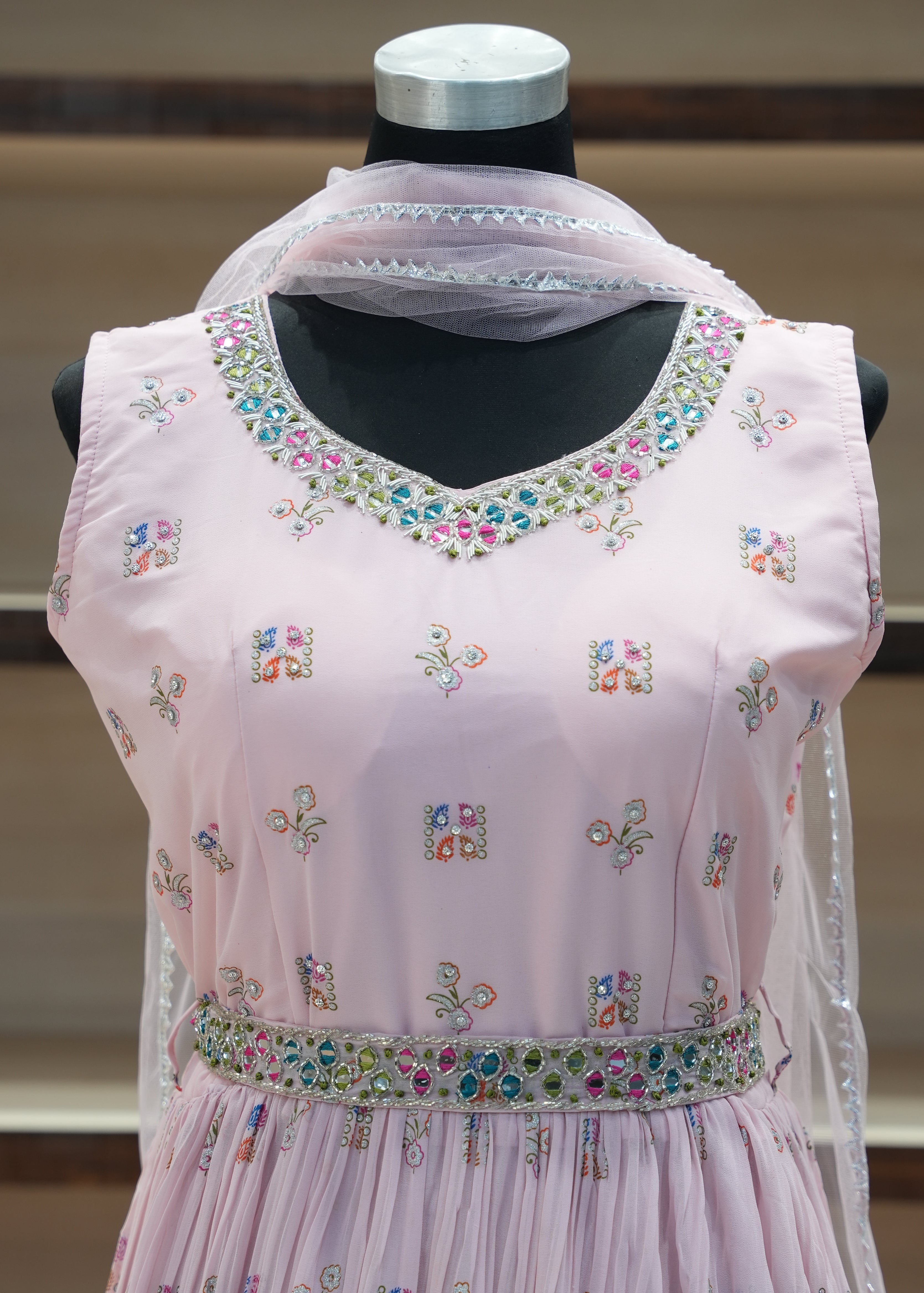Pink blouse with floral embroidery on a mannequin against a neutral background