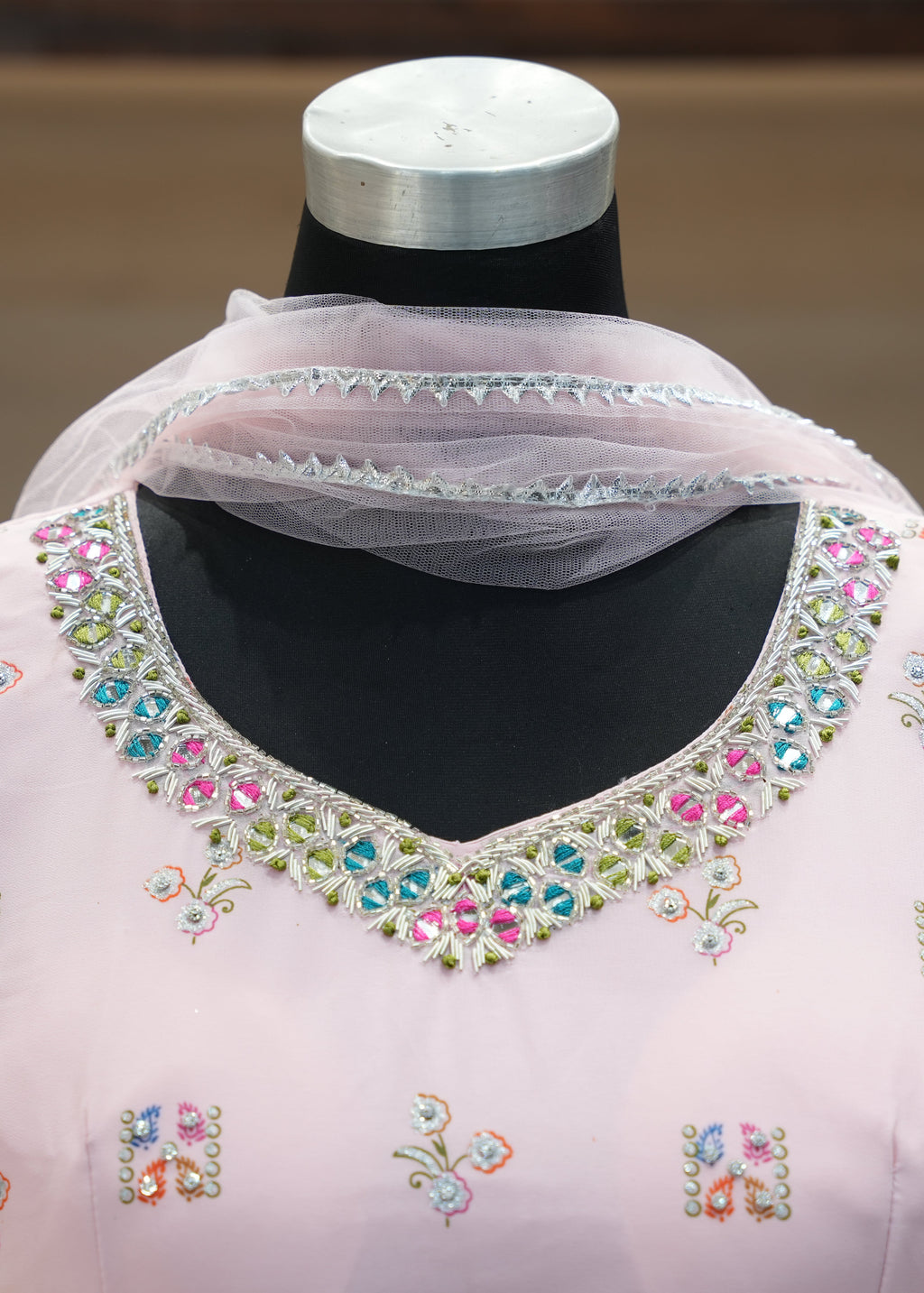 Pink embroidered blouse on a mannequin with a blurred background