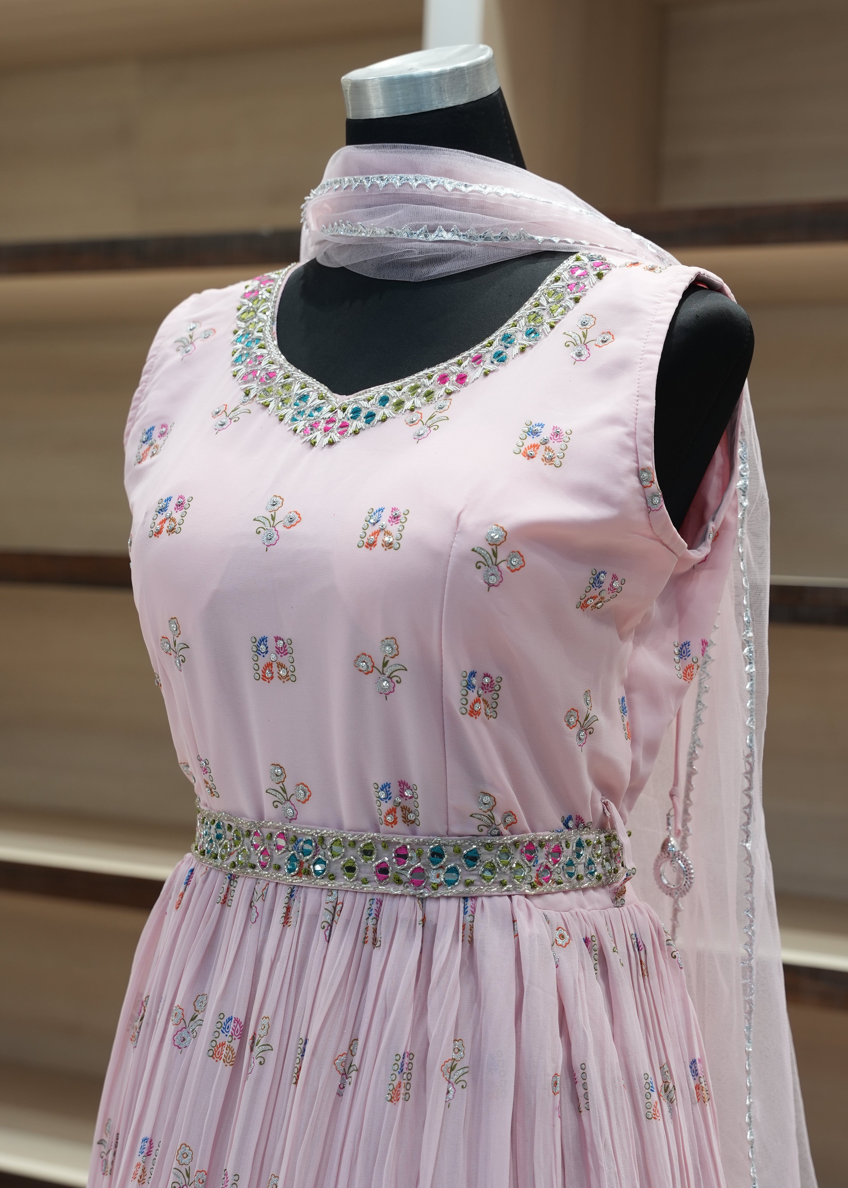 Pink dress with floral embroidery on a mannequin against a neutral background