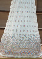 White embroidered fabric on a wooden surface with a neutral background