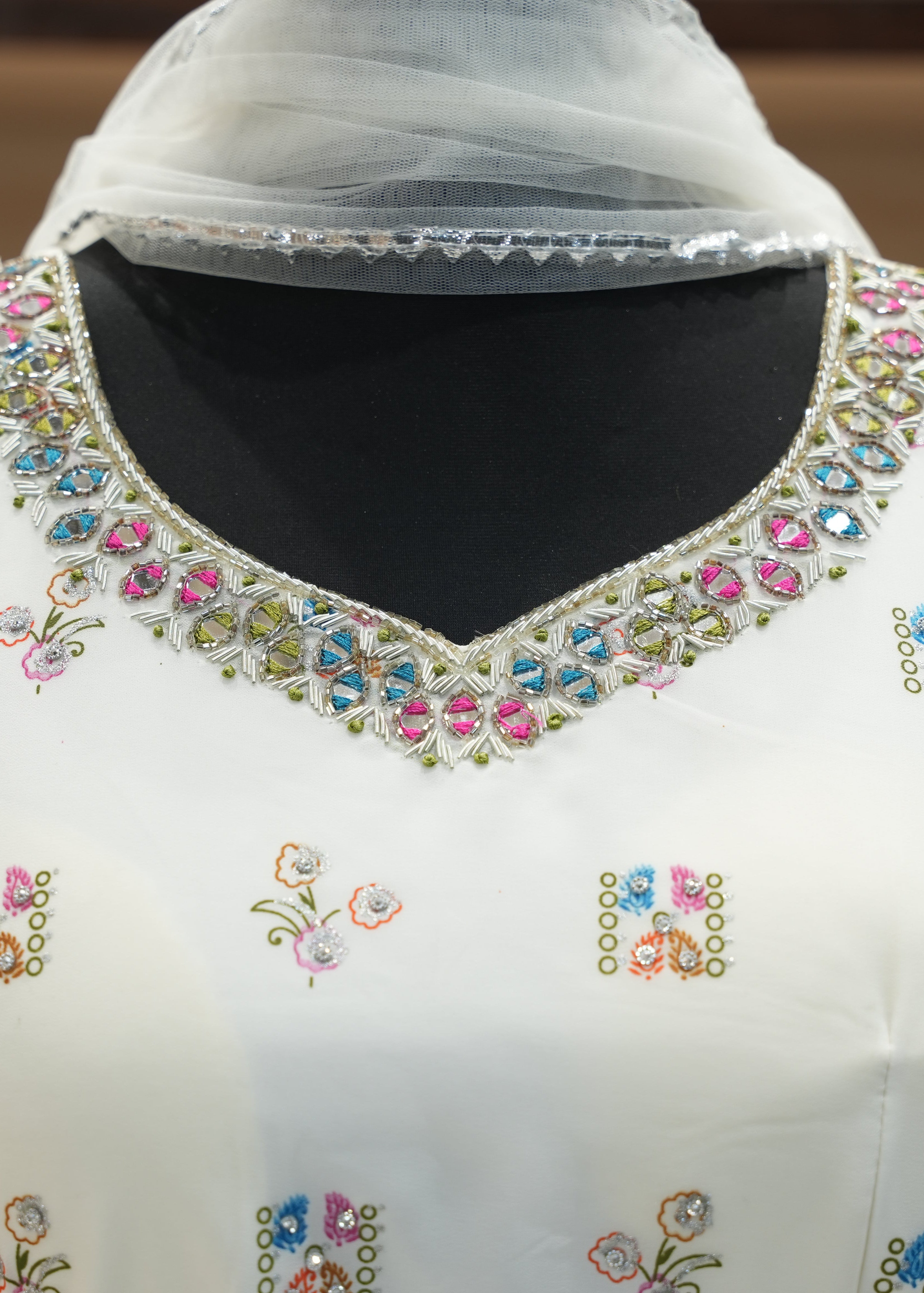 White garment with colorful embroidery on a mannequin