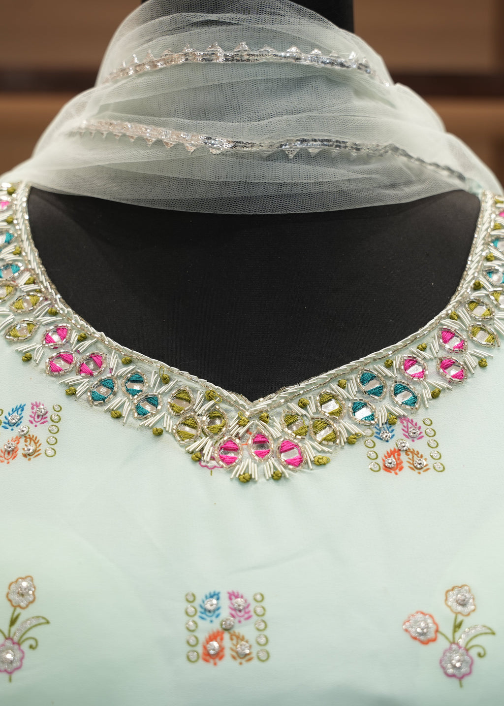 Light blue garment with colorful embroidery on a plain background