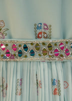 Close-up of a light blue fabric with floral embroidery and decorative border.