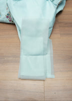 Light blue garment with floral embroidery on a wooden surface