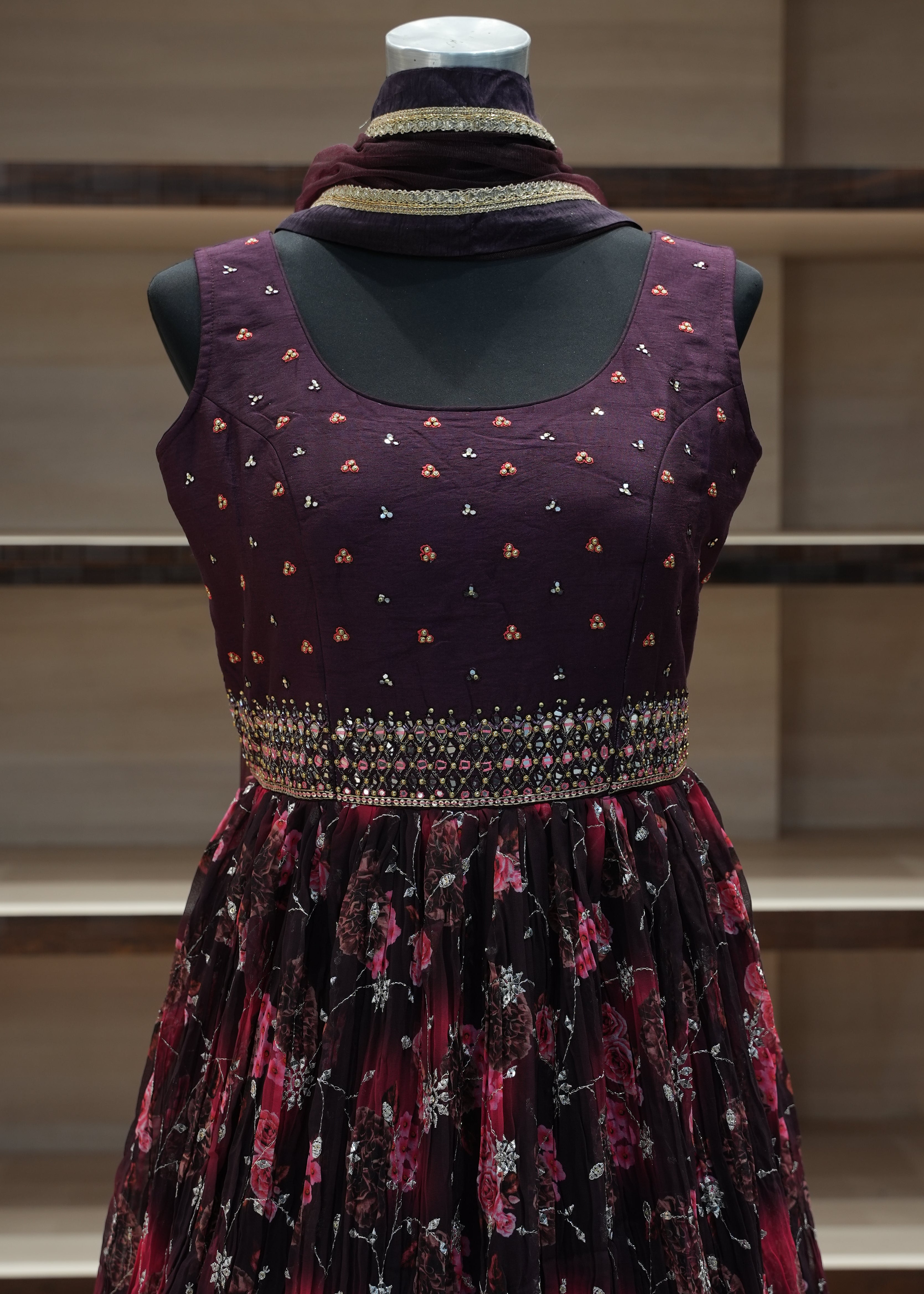 Mannequin wearing a dark purple dress with floral patterns against a neutral background