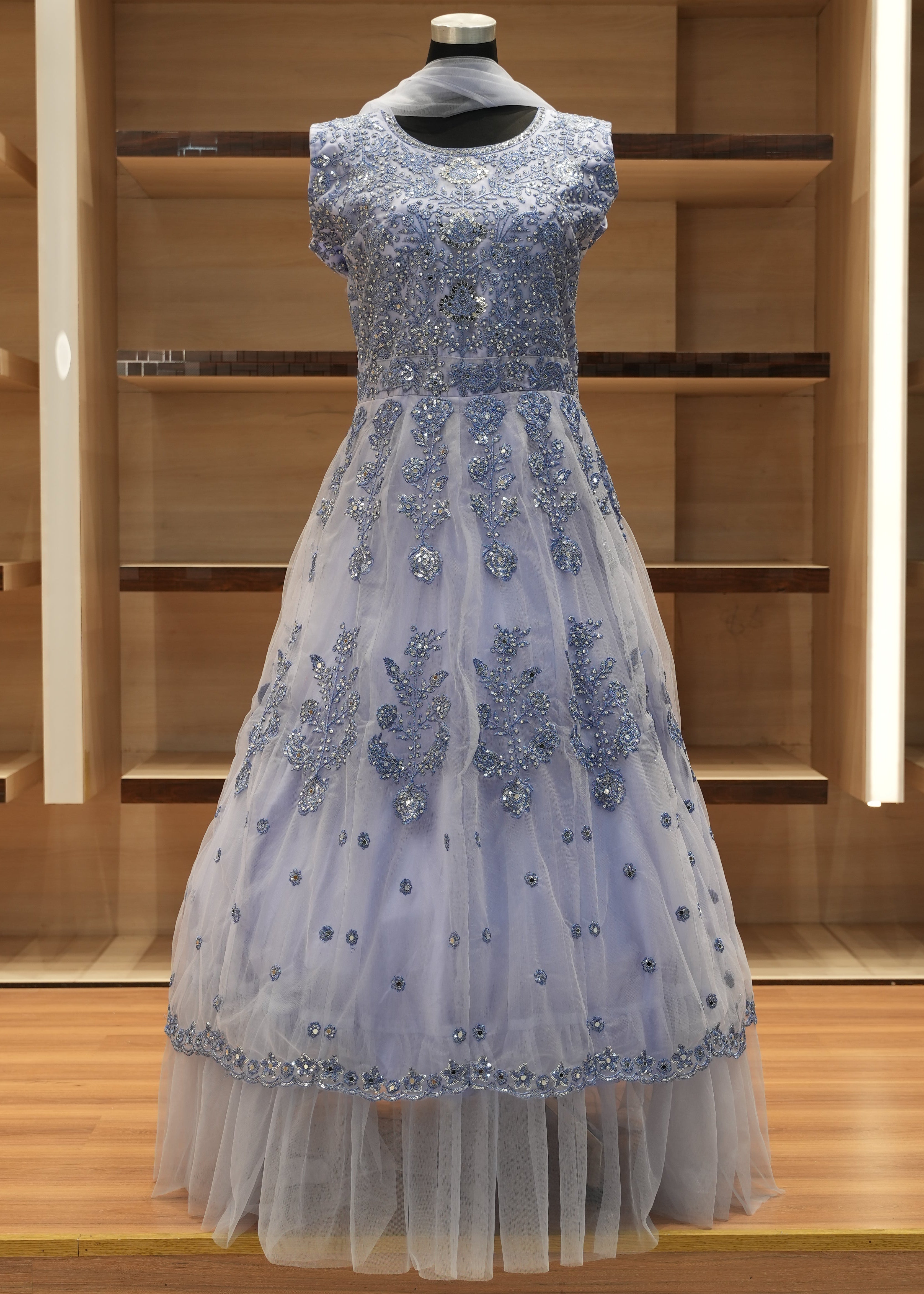 Elegant silver evening gown on a mannequin against a wooden panel background