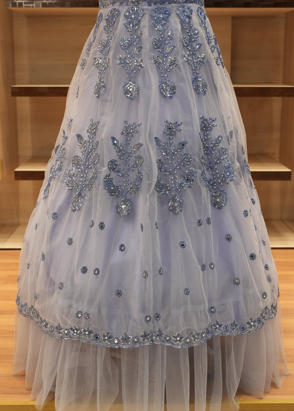 Elegant white dress with blue embellishments hanging against a wooden background