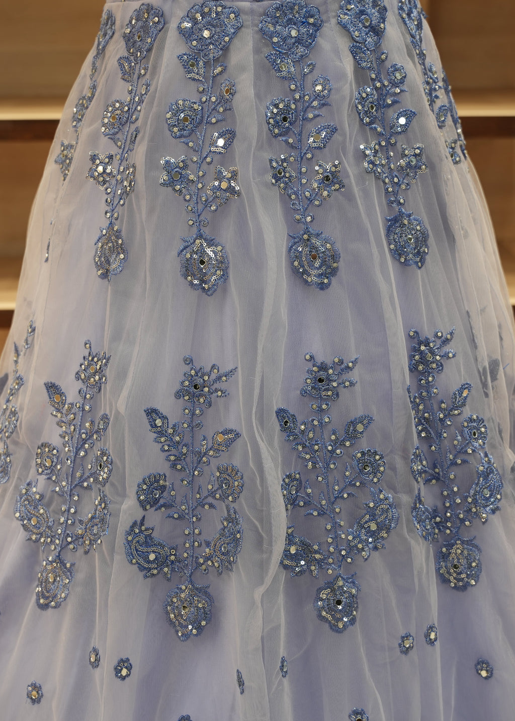 Blue embroidered dress with intricate patterns on a wooden floor.