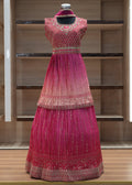 Mannequin wearing a pink traditional outfit with intricate designs against a wooden background