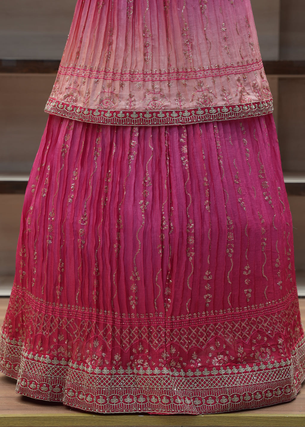 Pink saree with intricate patterns on a wooden surface