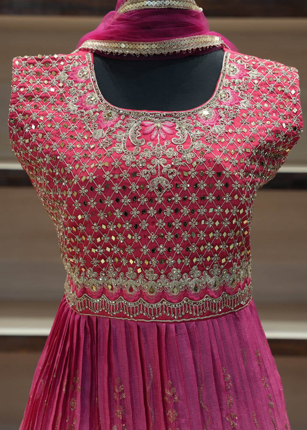 Pink embroidered dress on a mannequin with a blurred background