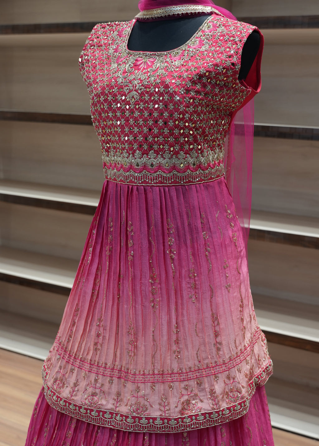Pink dress with intricate detailing on a mannequin against a neutral background