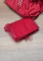 Red fabric with floral embroidery on a wooden surface