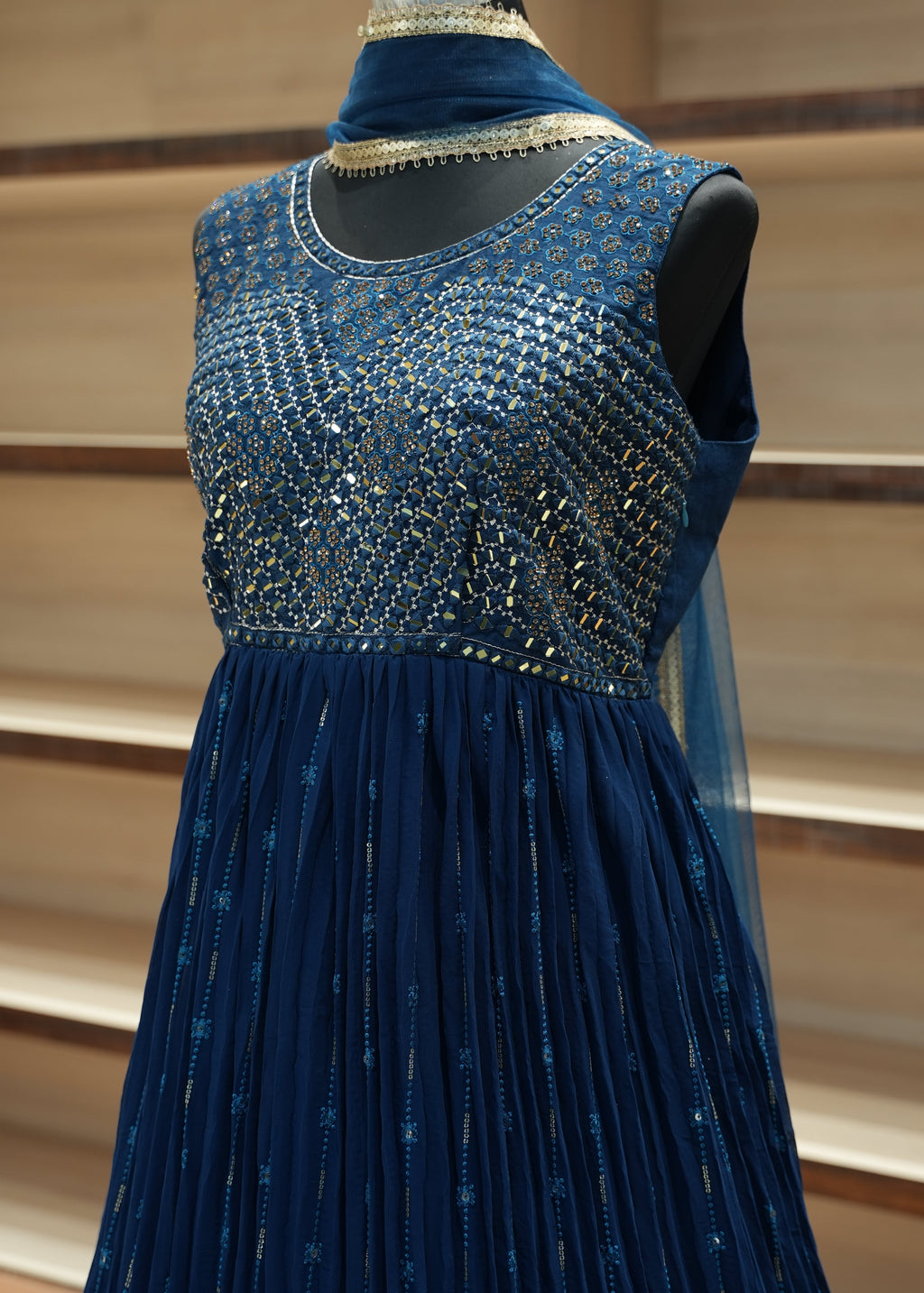 Close-up of a blue dress with intricate detailing on a neutral background