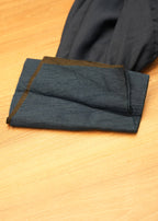 Folded dark blue fabric with a brown border on a wooden surface