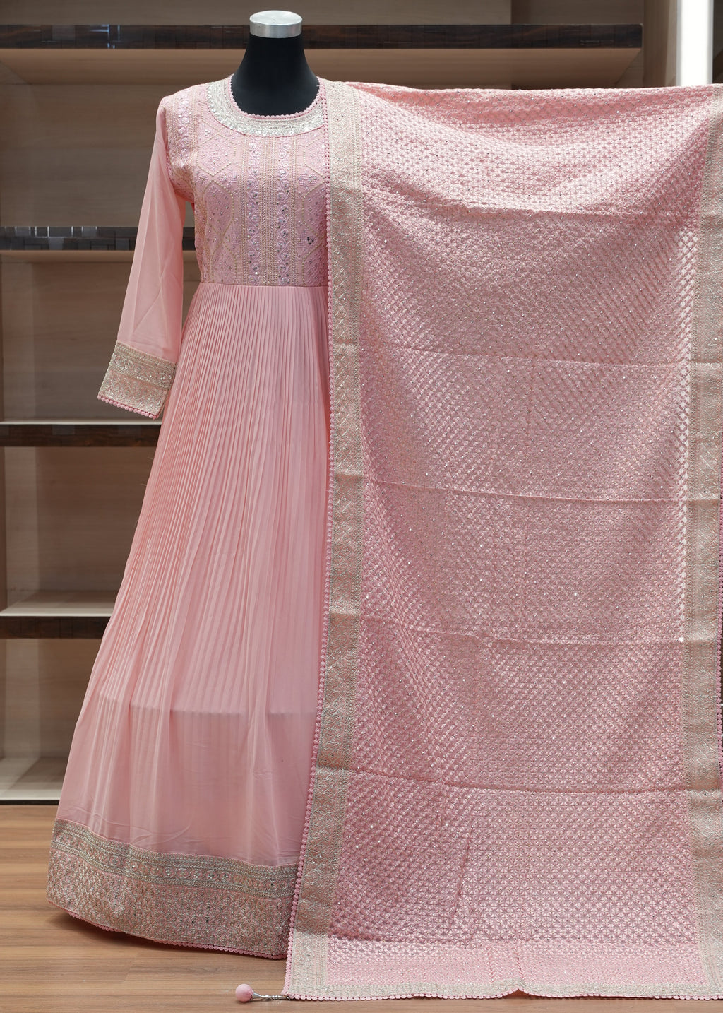 Pink saree with a textured pattern draped over a chair against a wooden panel background