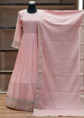 Pink saree with a textured pattern draped over a chair against a wooden panel background