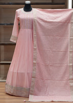 Pink saree with a textured pattern draped over a chair against a wooden panel background