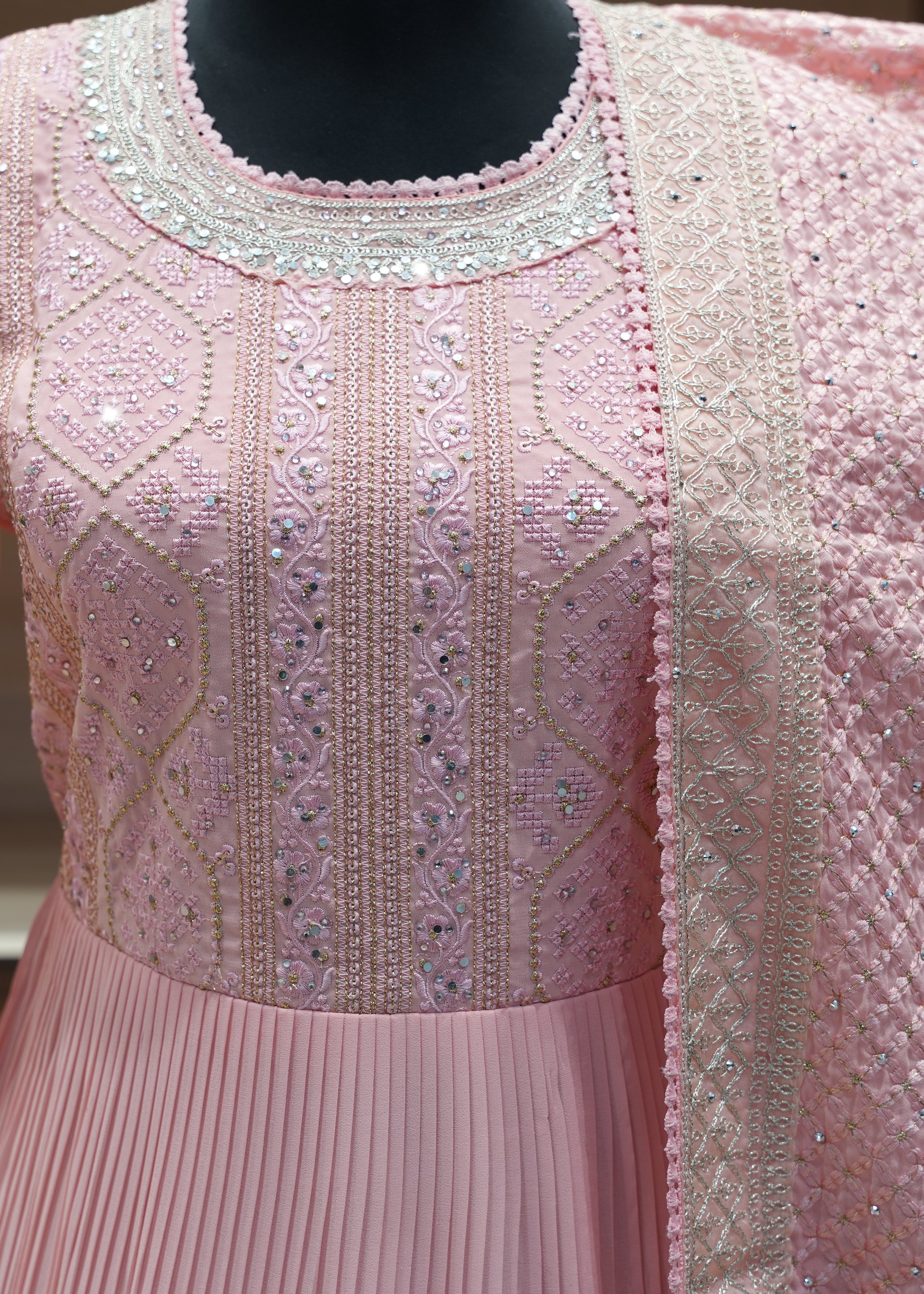 Pink embroidered dress on a mannequin with a blurred background