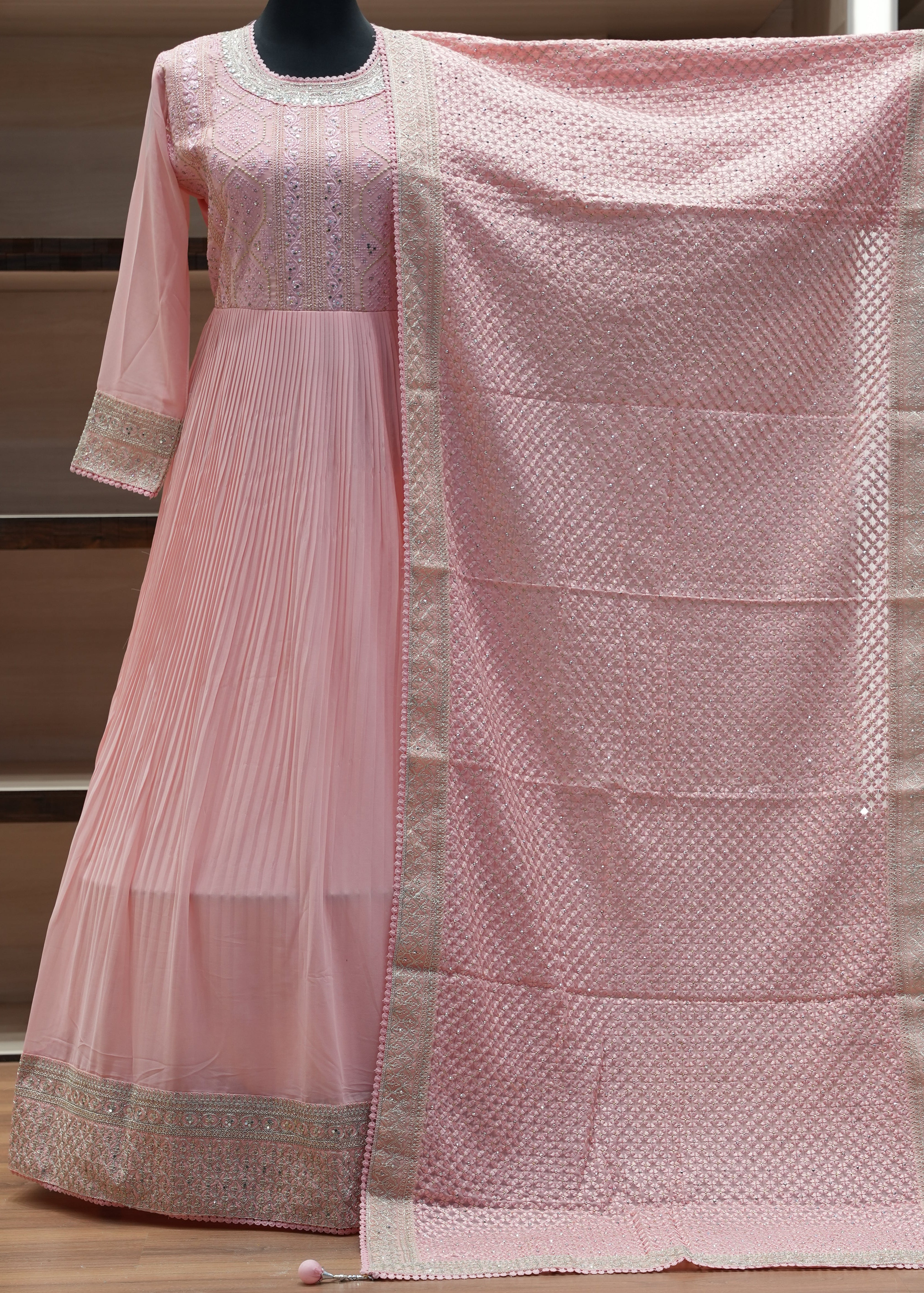 Pink saree with gold border draped over a chair