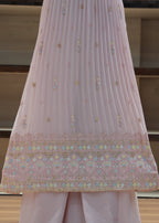 Pink embroidered fabric draped over a surface with a neutral background